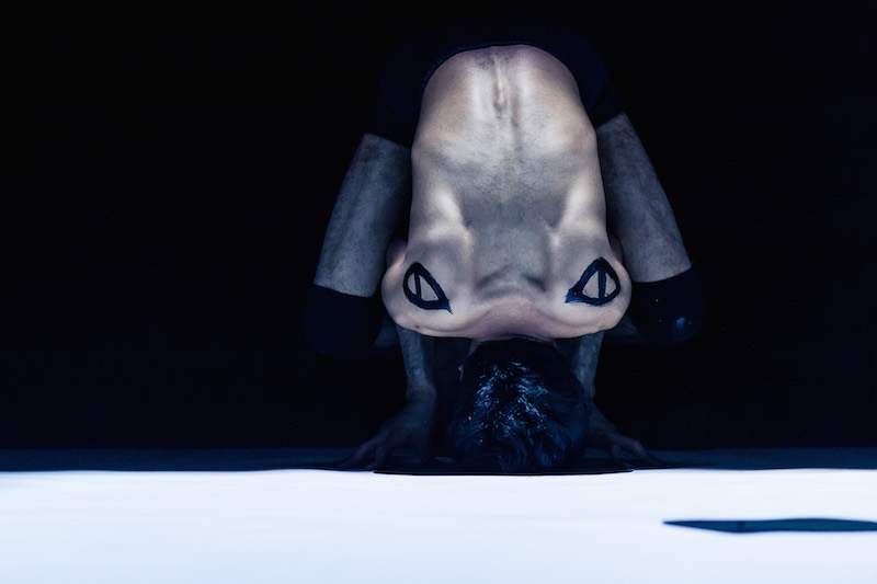 Odedra is curved forward on his names so ink-designed back is showing to the audience